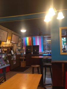 view of the Black Drop's pride flags from inside the lobby of the shop